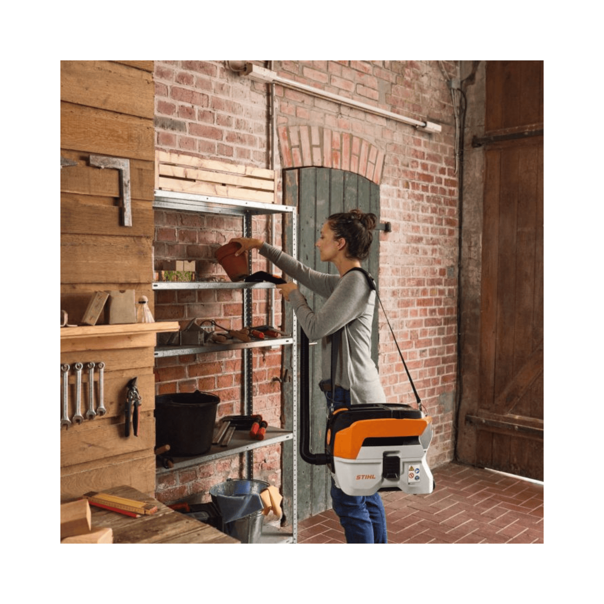 STIHL SEA 50 Cordless Vacuum Cleaner in use for home cleaning tasks on shelving unit.