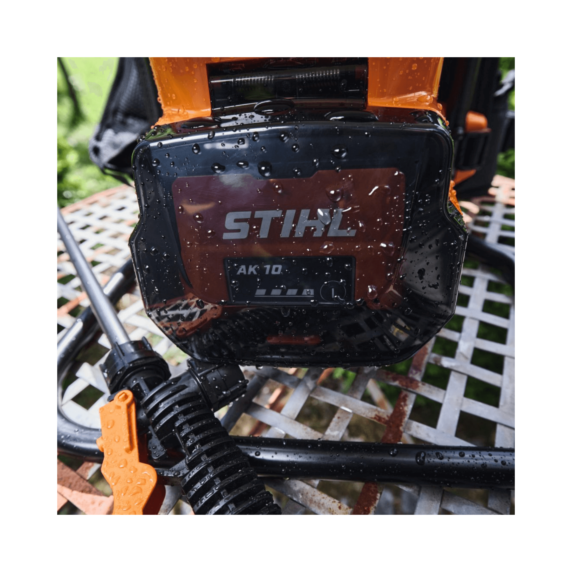 STIHL SGA 60 Cordless Sprayer battery pack displaying water droplets on a garden table.