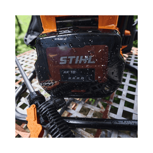 STIHL SGA 60 Cordless Sprayer battery pack displaying water droplets on a garden table.