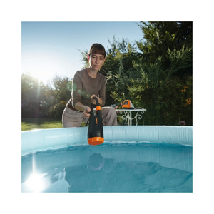 User operating the TPA 20 Cordless Pump to remove water from an inflatable pool in a sunny garden.