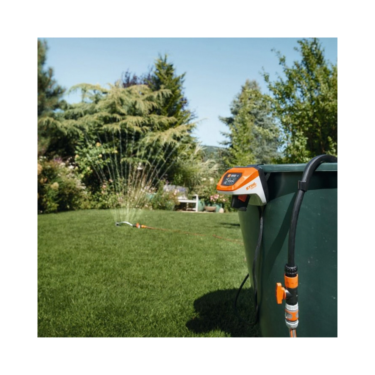 STIHL TPA 20 Cordless Pump connected to a water tank in a garden for irrigation.