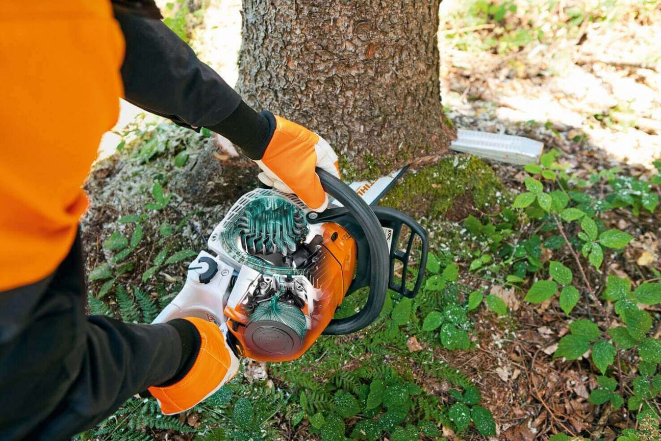 Person using a chainsaw to cut down a tree, showcasing safety gear and forestry equipment.
