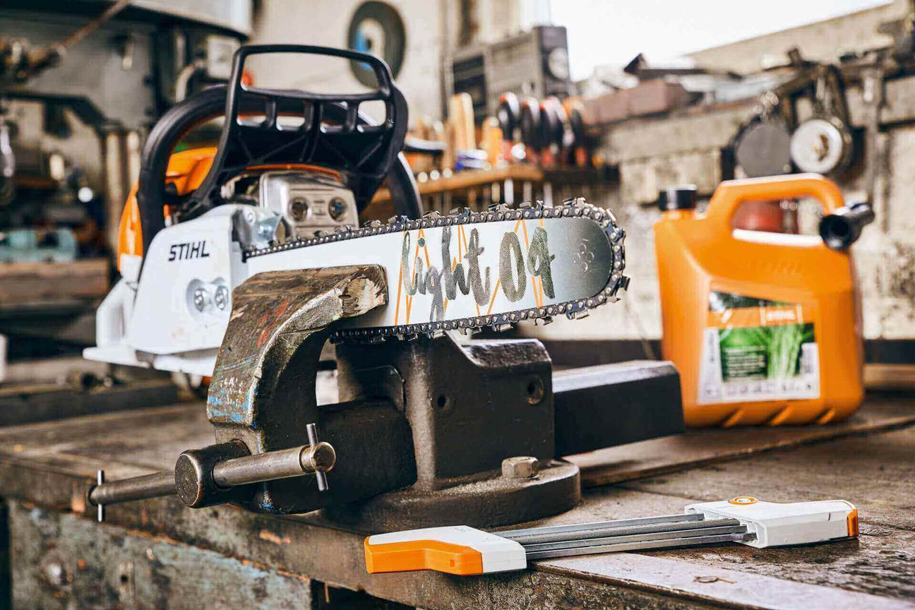 STIHL chainsaw on workbench with a vice and oil can, showcasing tools for woodworking and maintenance.