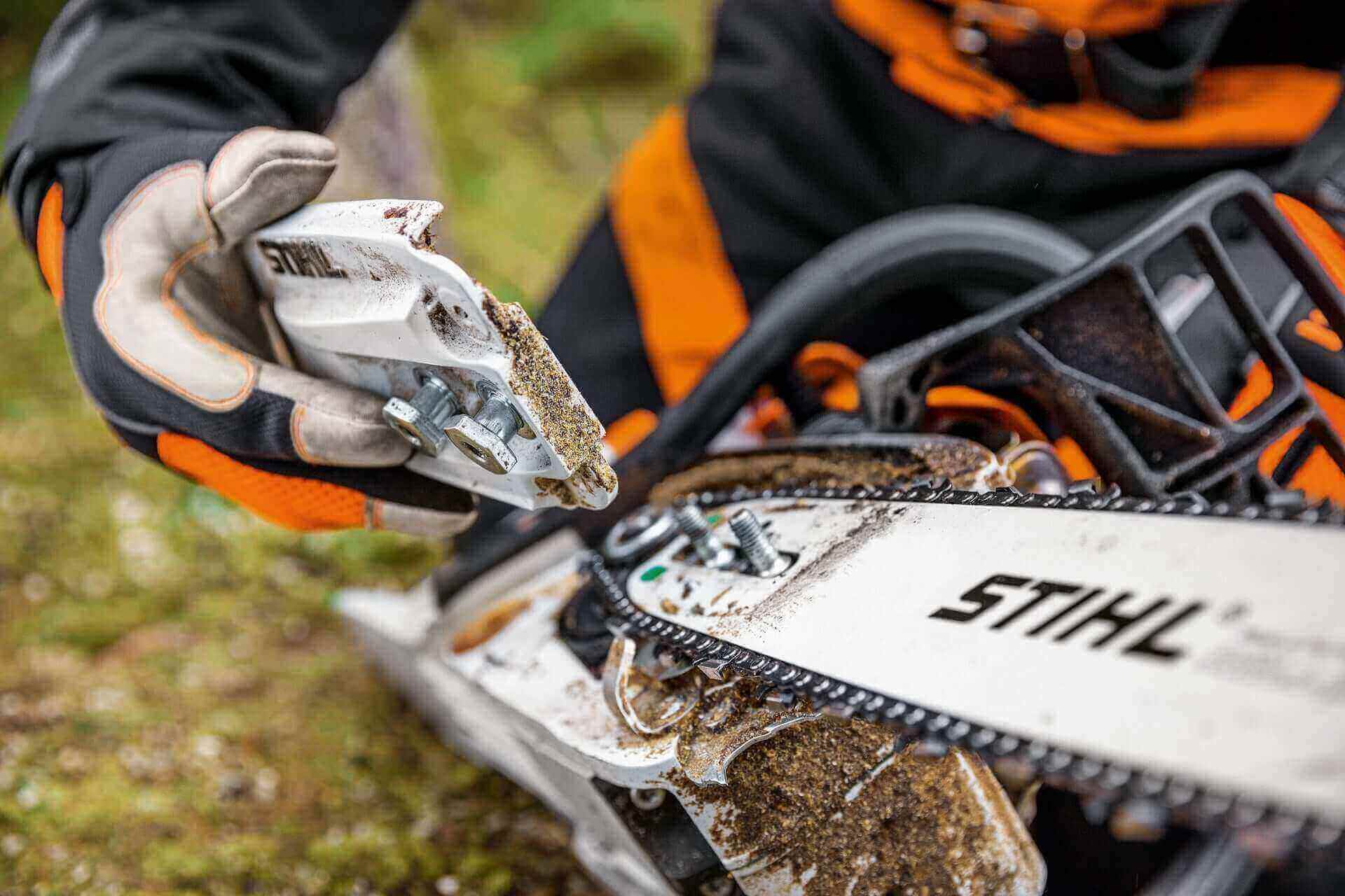 A close-up of a person holding a STIHL chainsaw tool, showcasing precision maintenance in an outdoor setting.
