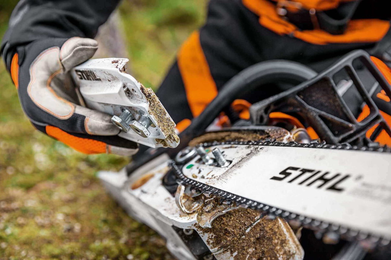 A close-up of a person holding a STIHL chainsaw tool, showcasing precision maintenance in an outdoor setting.