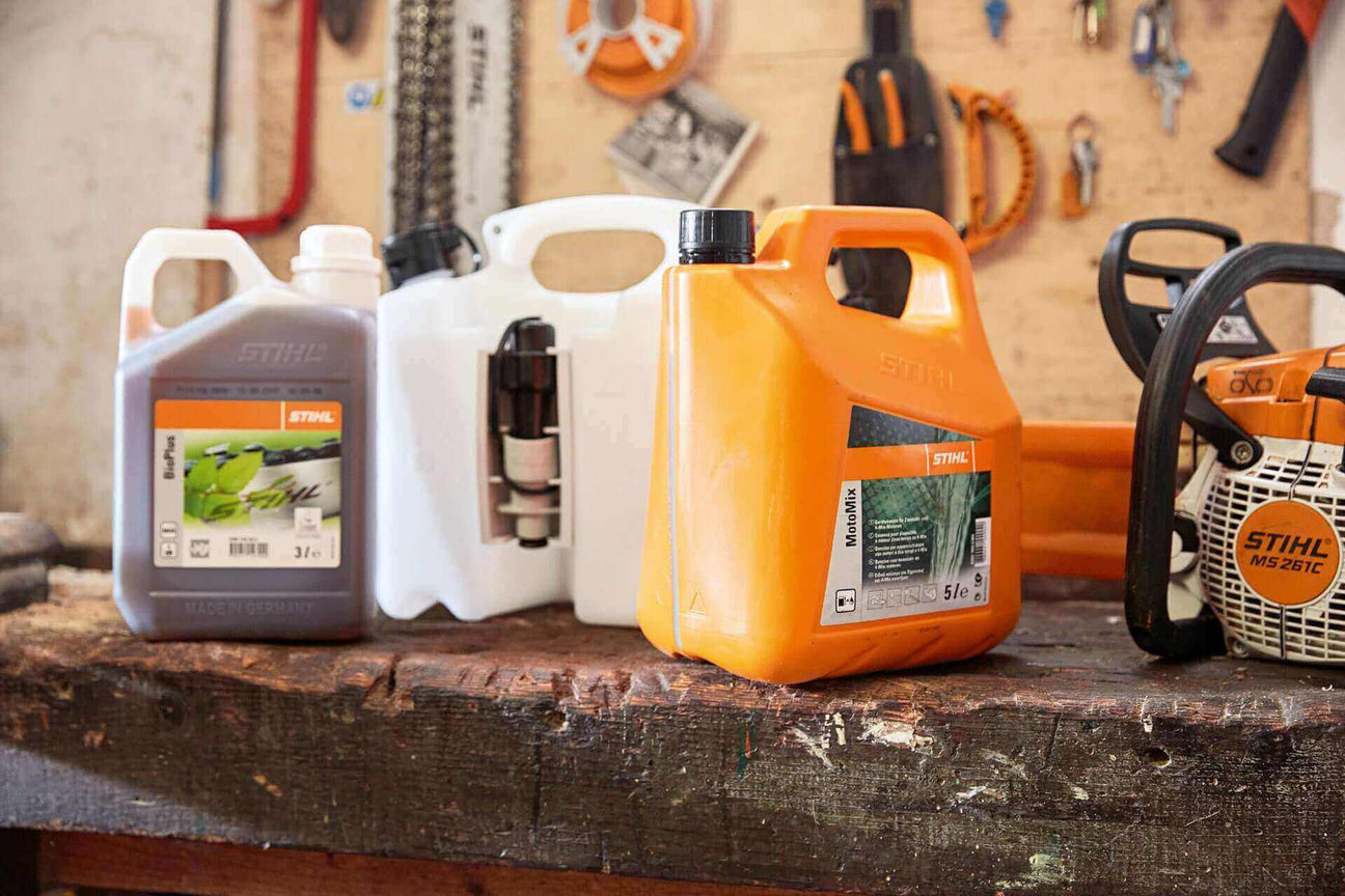 STIHL oil and fuel containers displayed on a workbench in a workshop, showcasing various garden equipment supplies.