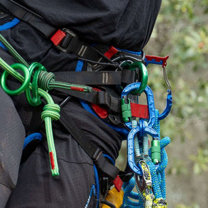 Close-up of climbing gear with colorful karaT carabiners attached to a harness for tree surgeons.