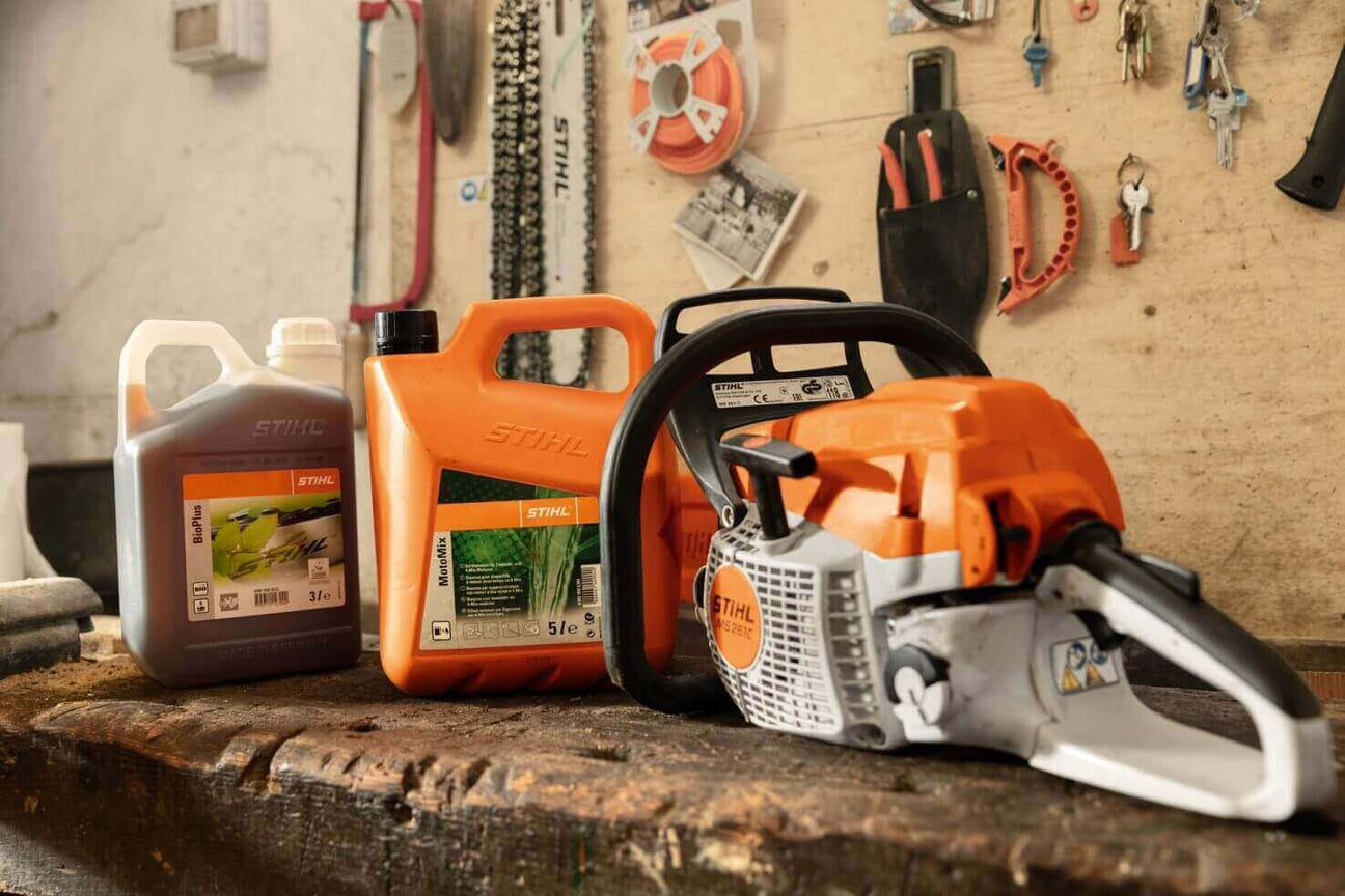 Stihl chainsaw with fuel containers on a wooden workbench in a workshop setting.
