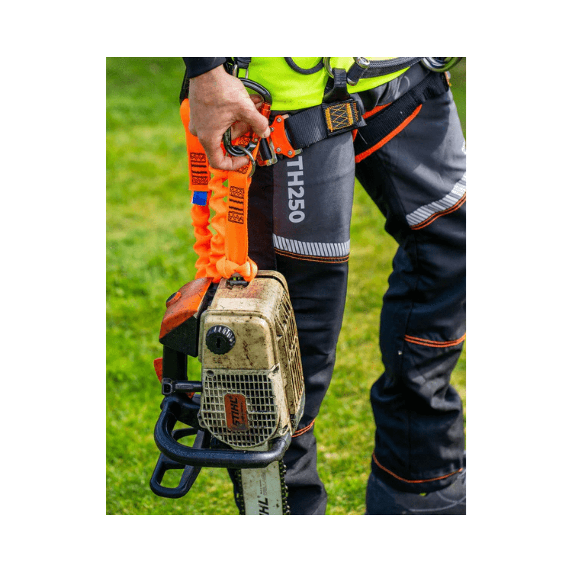 Person wearing Treehog TH250 Chainsaw Trousers holding a chainsaw outdoors, showcasing safety gear and tools for tree work.