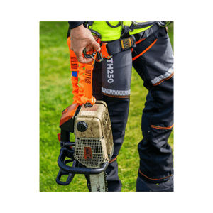 Person wearing Treehog TH250 Chainsaw Trousers holding a chainsaw outdoors, showcasing safety gear and tools for tree work.
