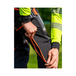 Close-up of a person adjusting the orange zip on Treehog TH250 chainsaw trousers, showcasing safety and comfort.