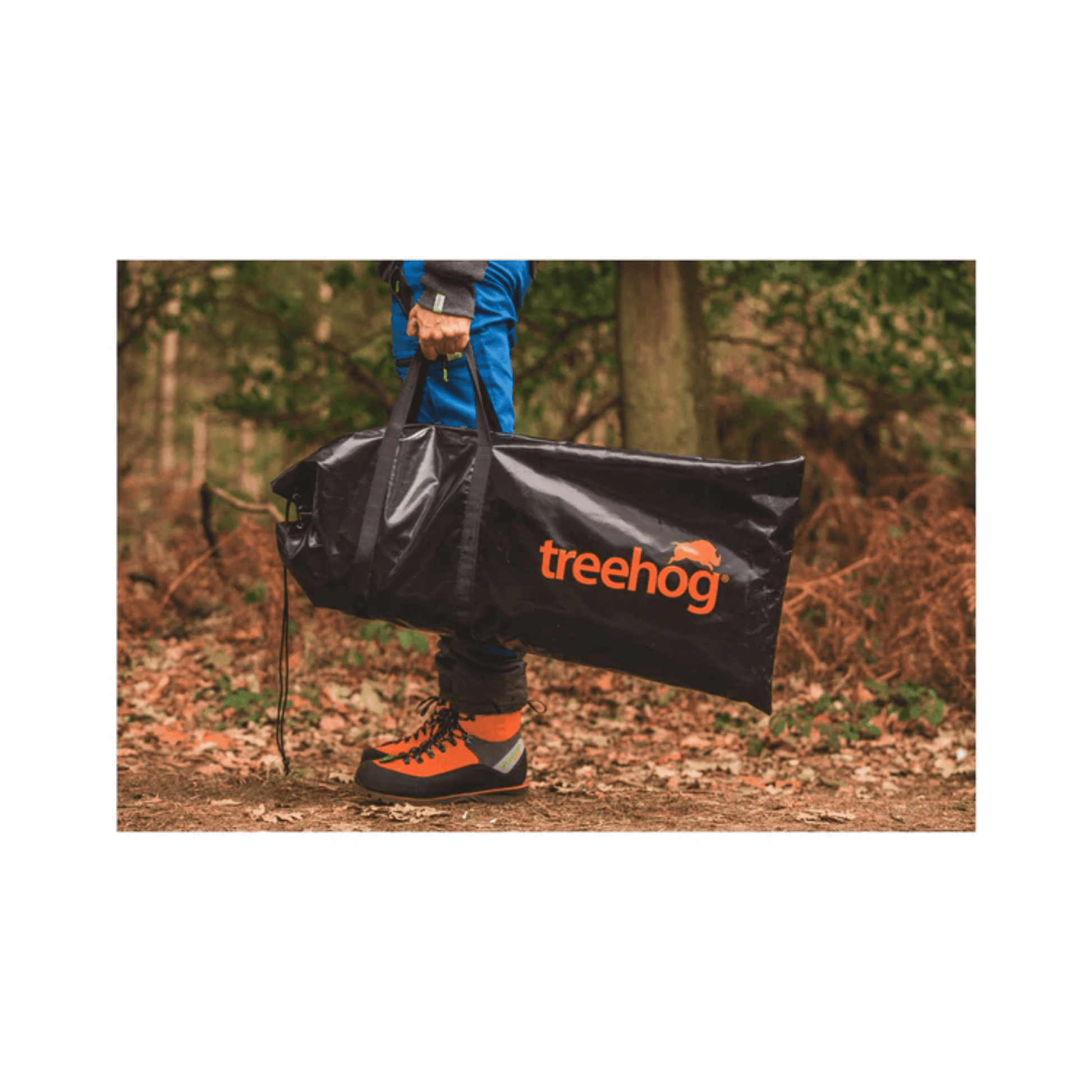 Person holding a TreeHog bag in a forest, showcasing its durable design for tree surgeons and outdoor enthusiasts.