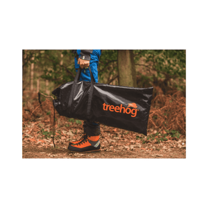 Person holding a TreeHog bag in a forest, showcasing its durable design for tree surgeons and outdoor enthusiasts.