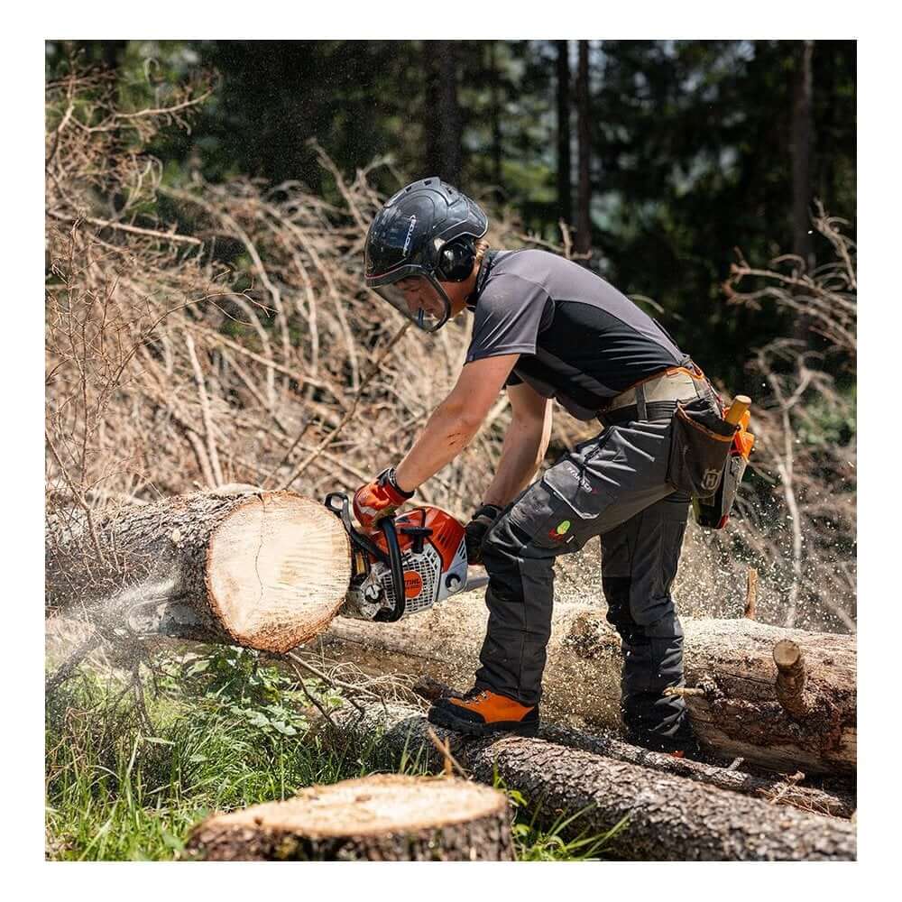Tree surgeon using a chainsaw to cut logs in a forested area, showcasing proper safety gear and professional work attire.