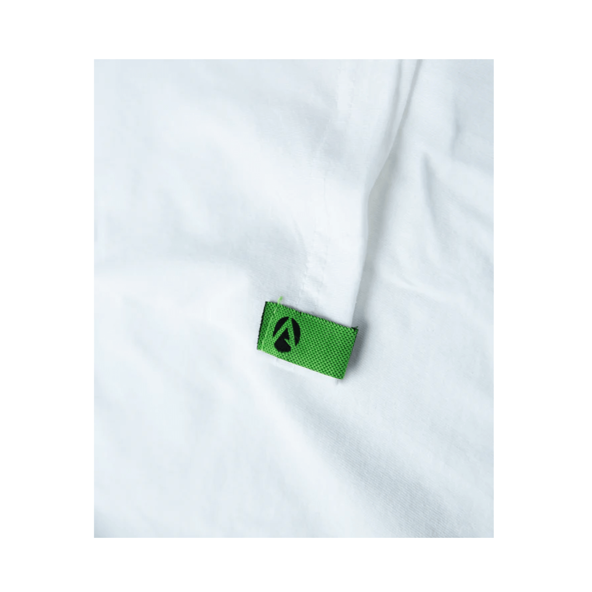 Close-up of the green label on a white short sleeve Arbortec t-shirt for tree surgeons, showcasing quality craftsmanship.