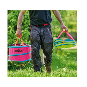 Person carrying two colorful Courant Pelican throwline bags for tree surgeons in a grassy area.