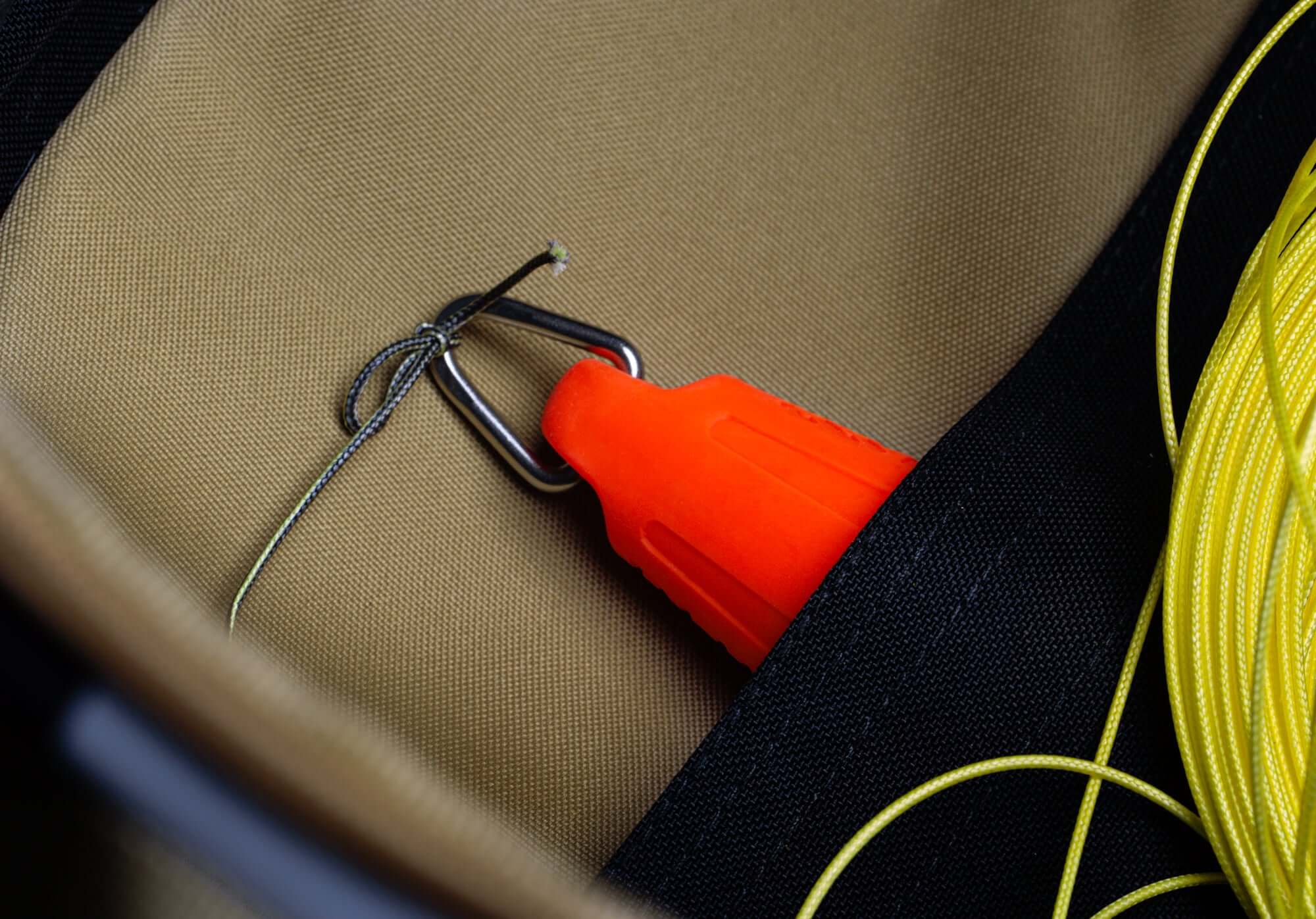 Close-up of a bright orange throwline tool with a hook, nestled in a foldable waterproof bag, ideal for tree surgeons.