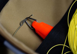 Close-up of a bright orange throwline tool with a hook, nestled in a foldable waterproof bag, ideal for tree surgeons.
