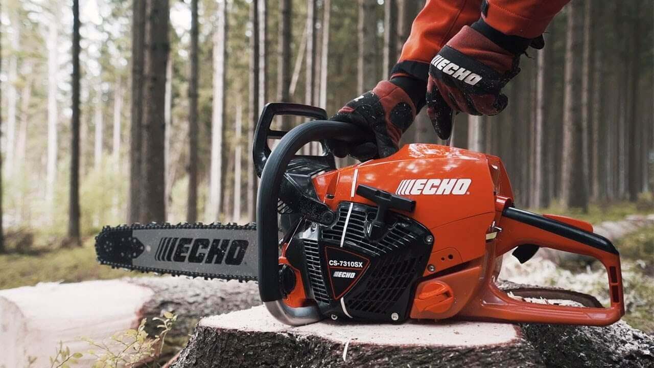 Tree surgeon using an Echo chainsaw to cut a log in a lush forest setting.
