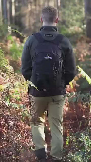 Man wearing Arbortec NomadX backpack while hiking through a forest, showcasing its outdoor versatility and comfort.