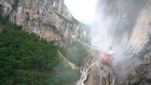 Climber wearing a harness at a misty cliff face, showcasing the challenges of climbing and mountain work.