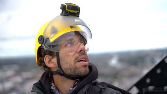 A person wearing a Petzl Strato climbing helmet and headlamp, looking upwards while at height, showcasing safety gear for tree surgeons.