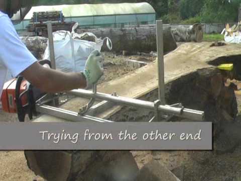 Tree surgeon using Granberg MKIII handle and rail set on a log for milling, demonstrating equipment adjustment.