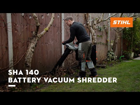 Man using SHA 140 Cordless Leaf Vacuum Shredder in a garden for efficient leaf clearance.