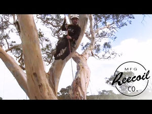 Tree surgeon using REECOIL Full Reach chainsaw lanyard for safe climbing and cutting in a tree.