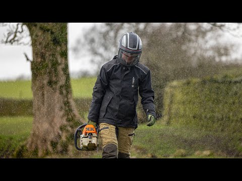 Tree Surgeon in waterproof smock holding chainsaw in rain, showcasing durability and protection in harsh conditions.