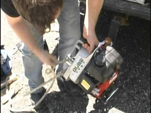 Person using a portable winch with a strap, demonstrating off-road recovery for tree surgeon applications.