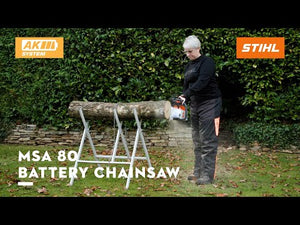 Person using MSA 80 C-B Cordless Chainsaw Timbersports 40th Edition on a log in a garden.