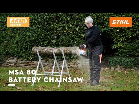 Person using MSA 80 C-B Cordless Chainsaw Timbersports 40th Edition on a log in a garden.