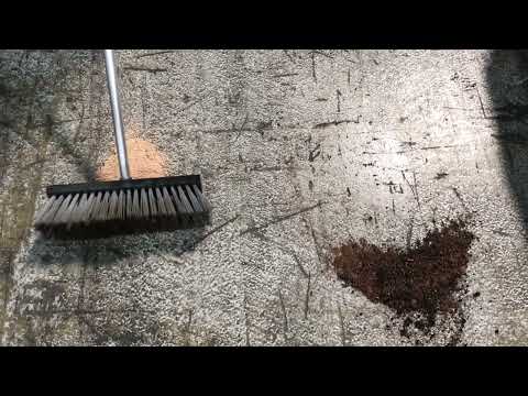 XT 15L Bag Organic Binder being used to absorb spills on a surface with a broom in view.