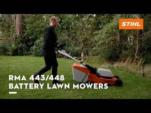 Man operating STIHL RMA 443/448 battery lawn mower on a lush green lawn.