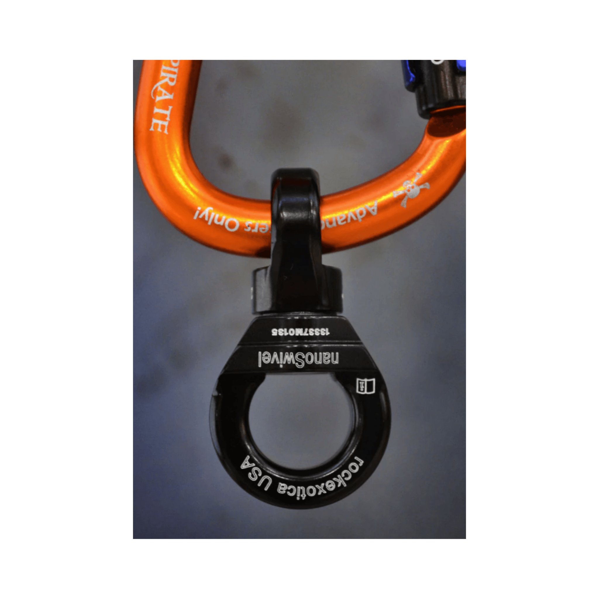 Rock Exotica NanoSwivel attached to an orange carabiner, showcasing its ultra-light design for climbing and rigging.