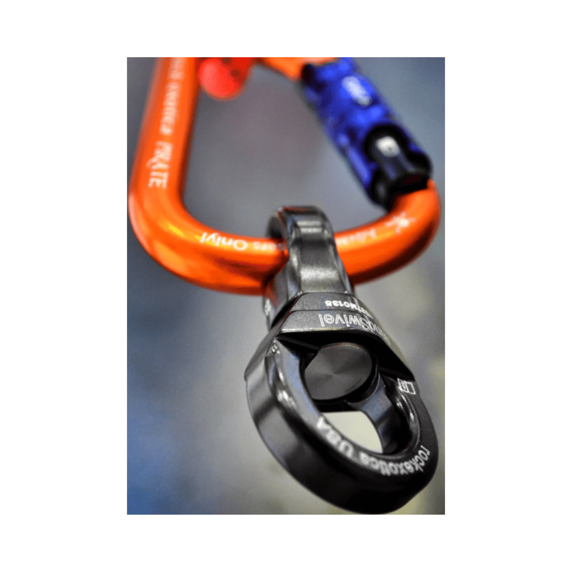 Close-up of Rock Exotica NanoSwivel attached to an orange carabiner, highlighting its lightweight and compact design.