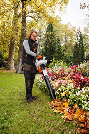 Person using a leaf blower in a garden.